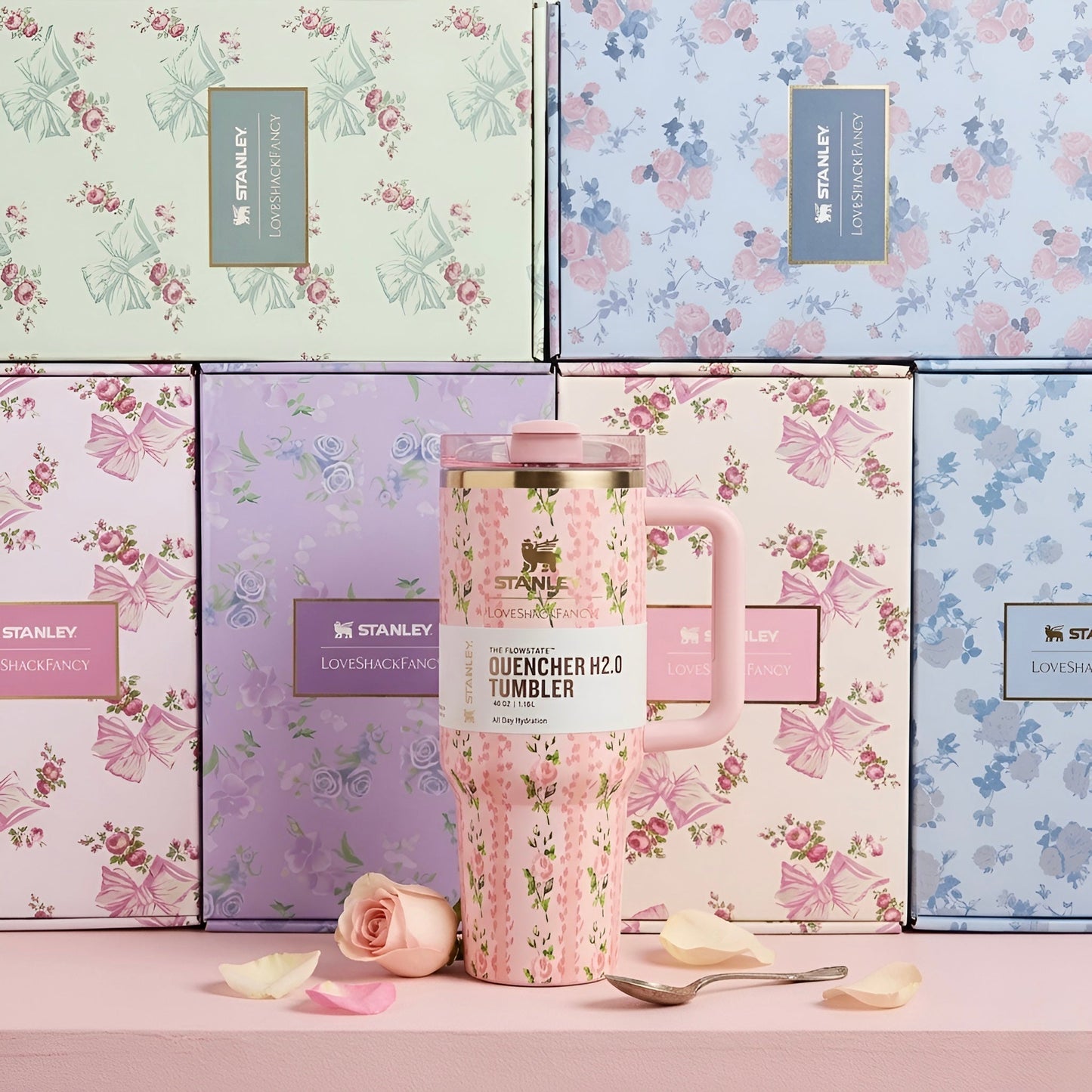 Pink floral stanley quencher h2.0 40 oz tumbler with gold-trimmed lid and matching handle in front of gift boxes
