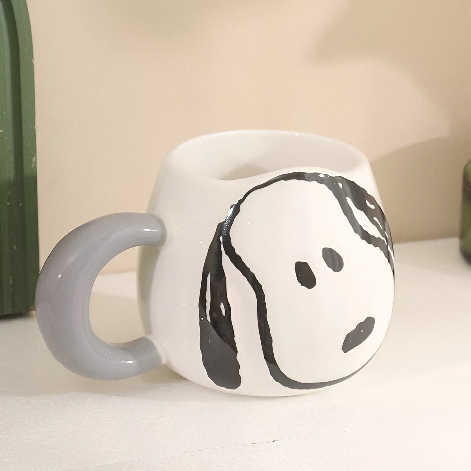 Bijela keramička šalica s sivom ručkom i crnim crtežom Snoopy lica u proizvodu snoopy šaljica siva
