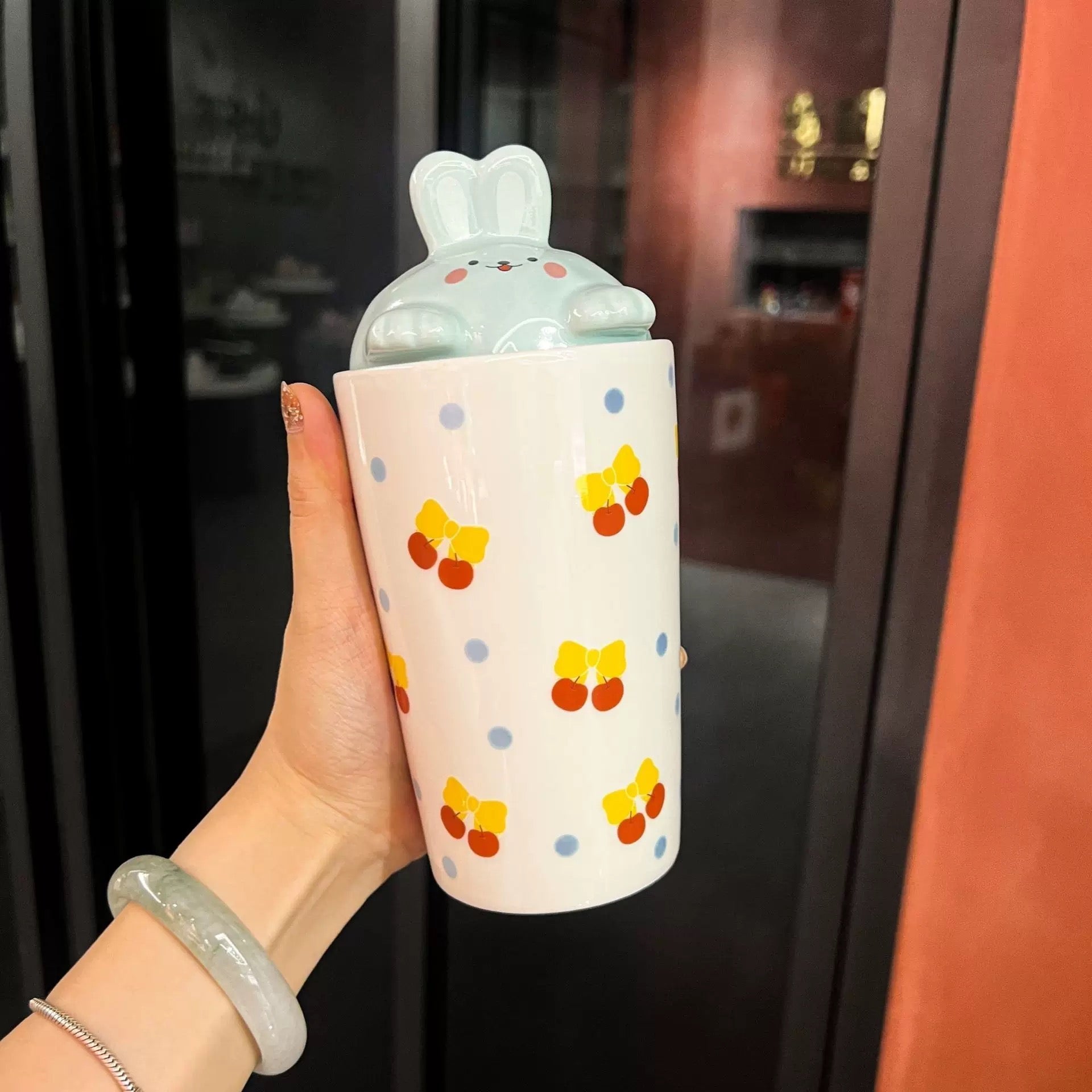 Bijela keramička čaša s poklopcem i slamkom, uzorak trešnje i zečić