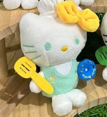 Hello kitty plišani privjesak bijeli plišani lik u mint zelenom pregaču s žutim mašnom i plavim rukavicama