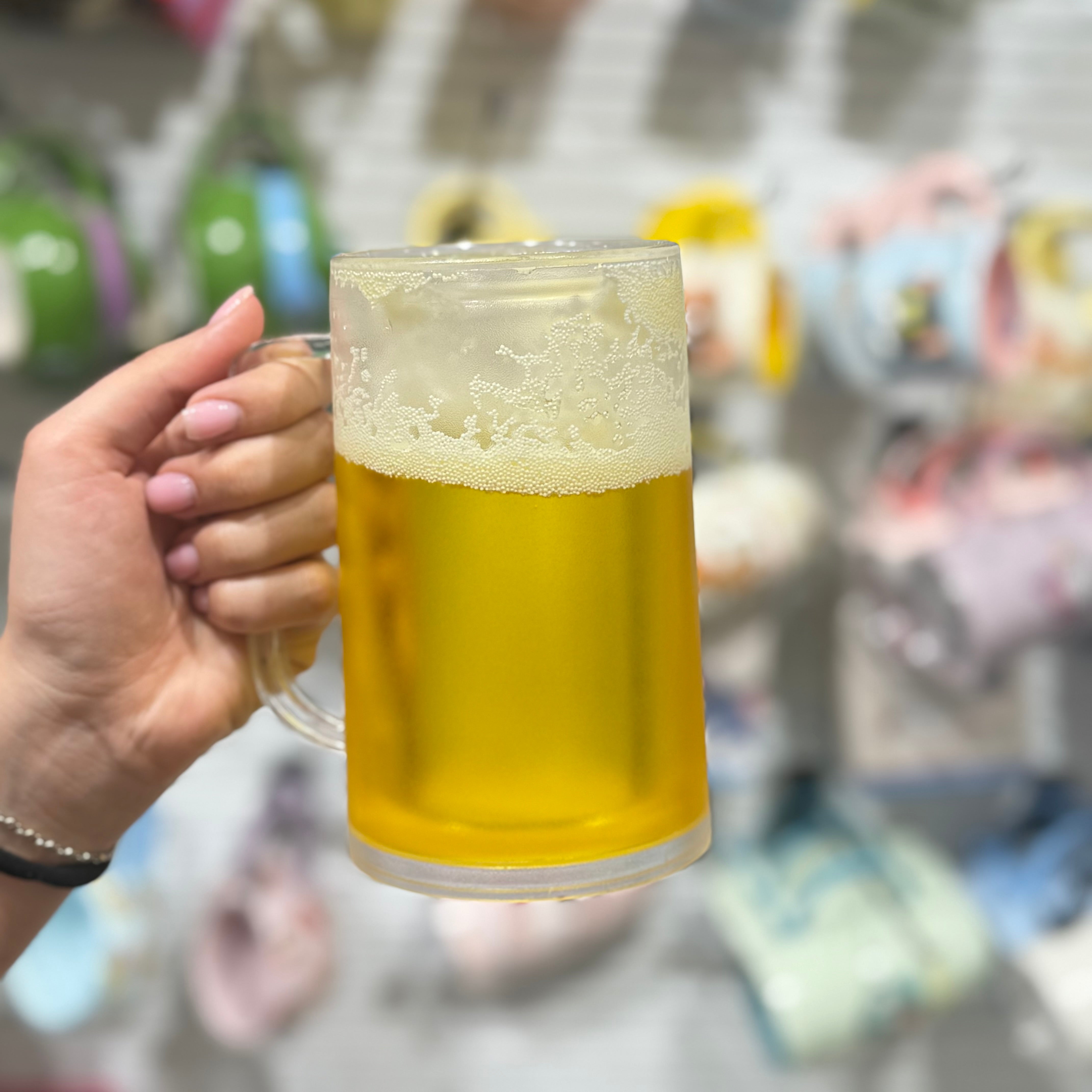 Frostirana staklena pivska šolja ledna krigla puna zlatnog piva s bijelom pjenom u ruci