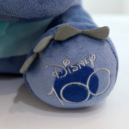 Plavi plišani jastuk stitch s vezanim disney 100 logom i sivom mašnom na nožici