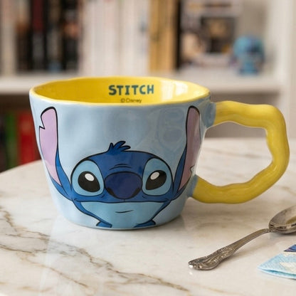 Plava i žuta keramička šalica s ilustracijom disneyjevog stora stitcha s ružičastim ušima na vanjskoj strani