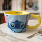 Plava i žuta keramička šalica s ilustracijom disneyjevog stora stitcha s ružičastim ušima na vanjskoj strani