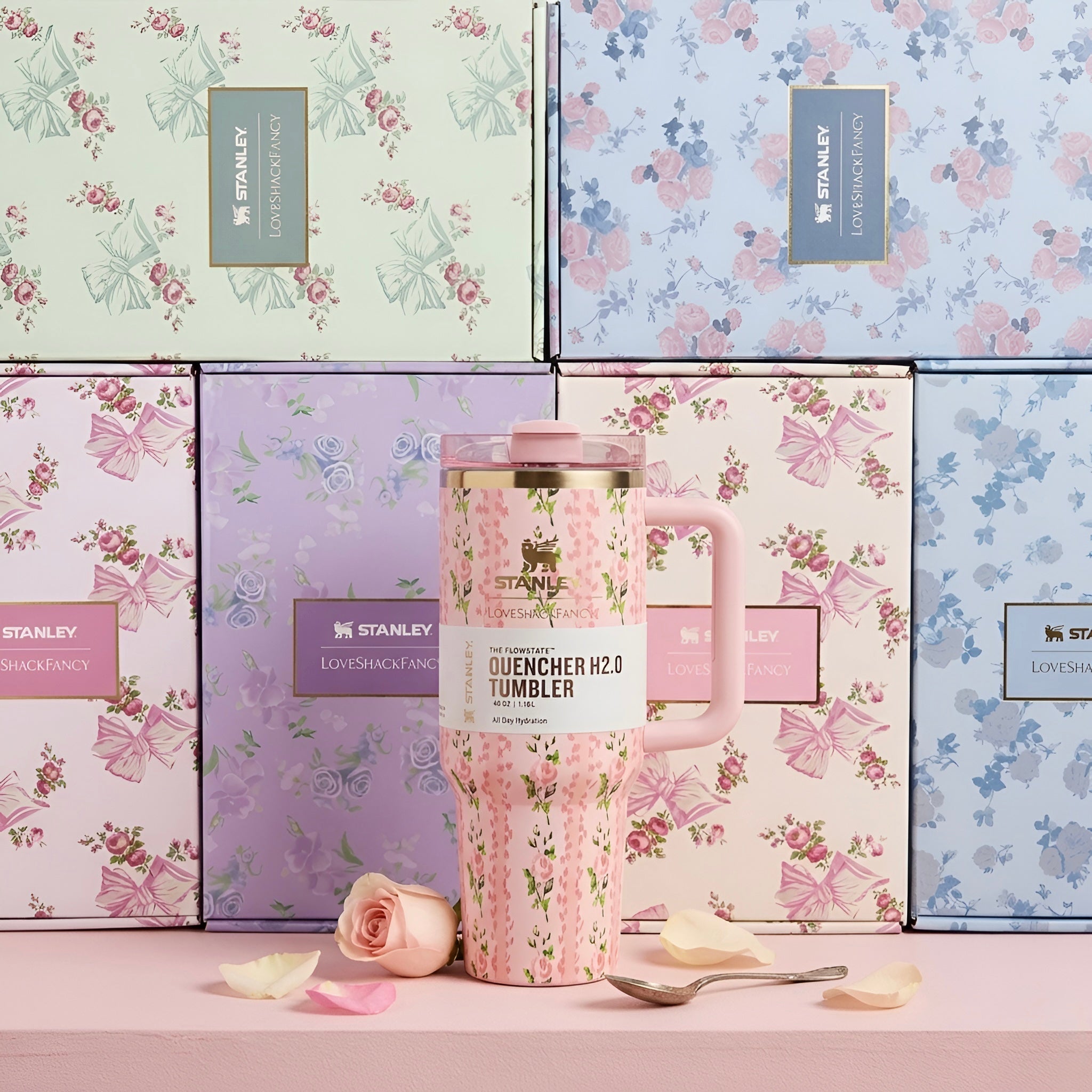 Pink floral stanley quencher h2.0 40 oz tumbler with gold-trimmed lid and matching handle in front of gift boxes