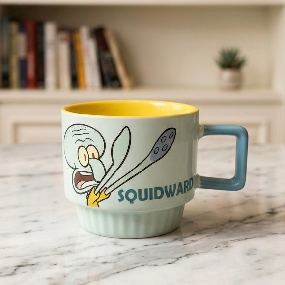 Svijetloplava keramička šalica squidward s žutim unutrašnjim dijelom i ilustracijom squidwarda s žlicama