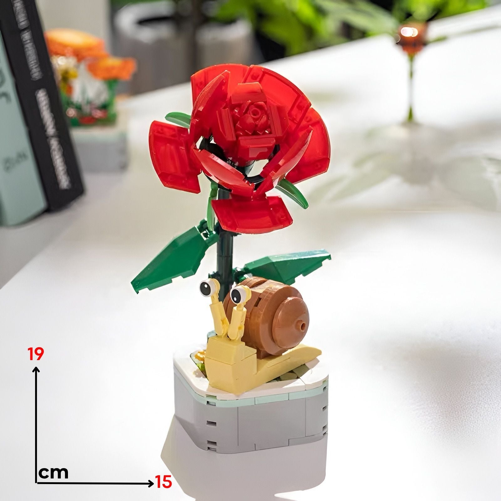 Vibrantna crvena lego ruža s zelenim listovima i smeđim pužem izrađena od plastičnih kocaka mali puž crvena ruža lego