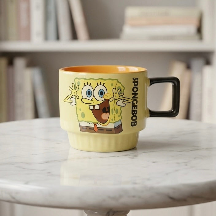 Žuta keramička šolja s veselim spongebob squarepants ilustracijom, crna drška i narančasti unutrašnjost